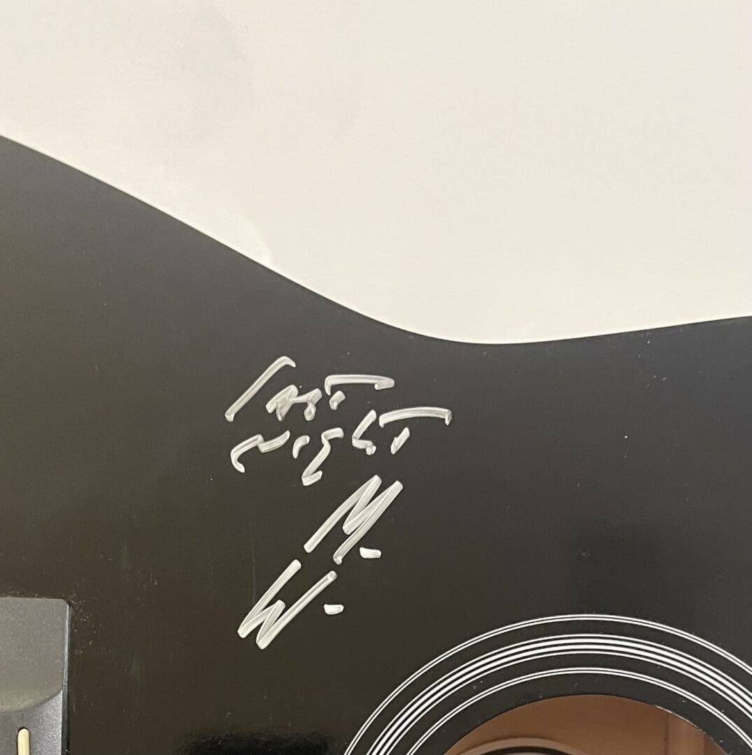 Signed black acoustic guitar close-up.