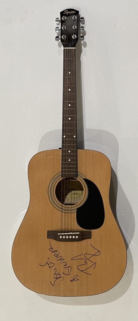 Acoustic guitar with autographs on body.
