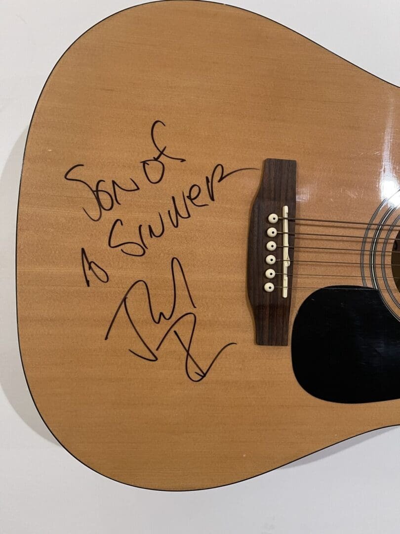 Acoustic guitar with handwritten signature and message.
