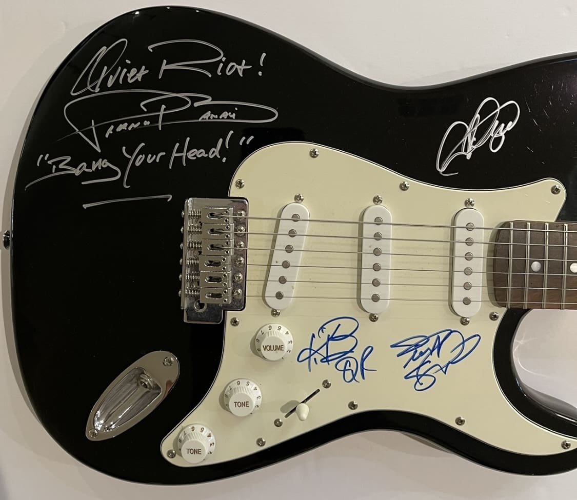 Black electric guitar with multiple signatures.