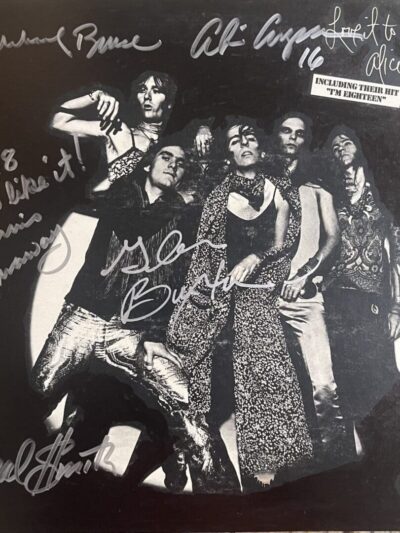 Rock band posing with autographs on album cover.