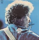 Musician with guitar on blue album cover.