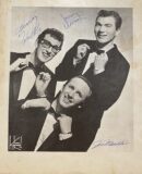 Three men in suits adjusting bow ties.