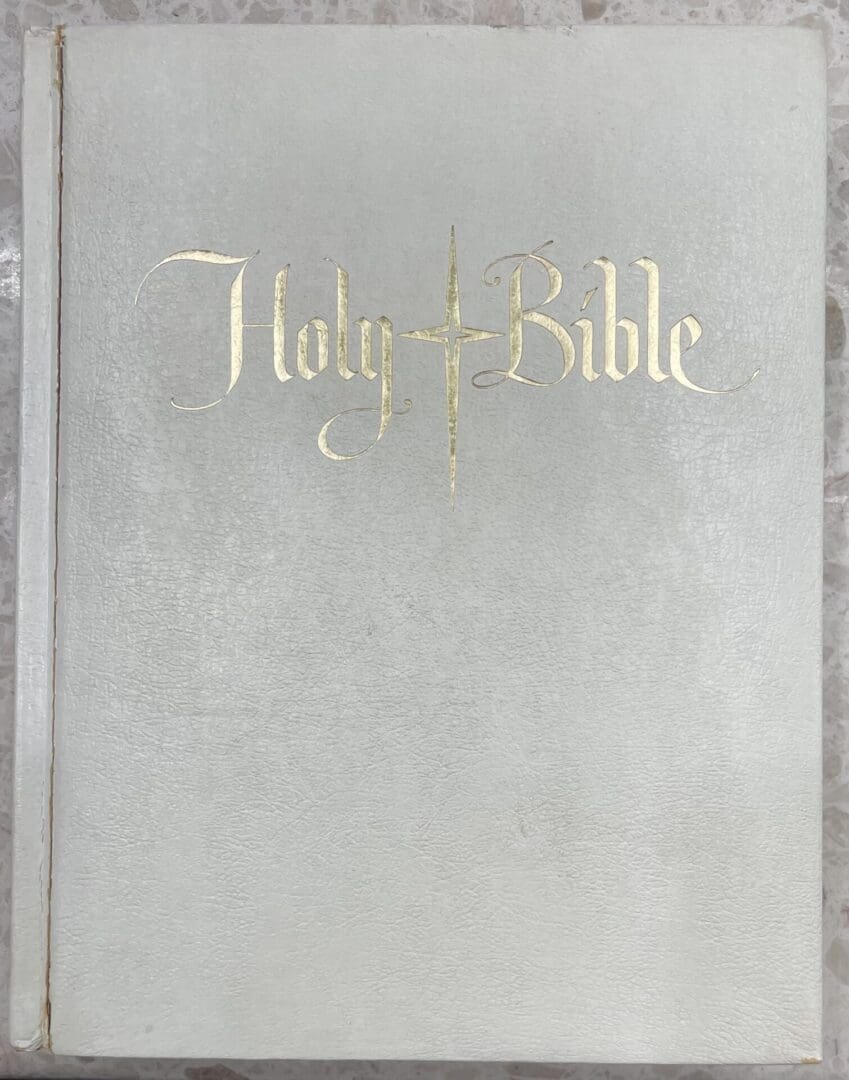 White Holy Bible with gold lettering.