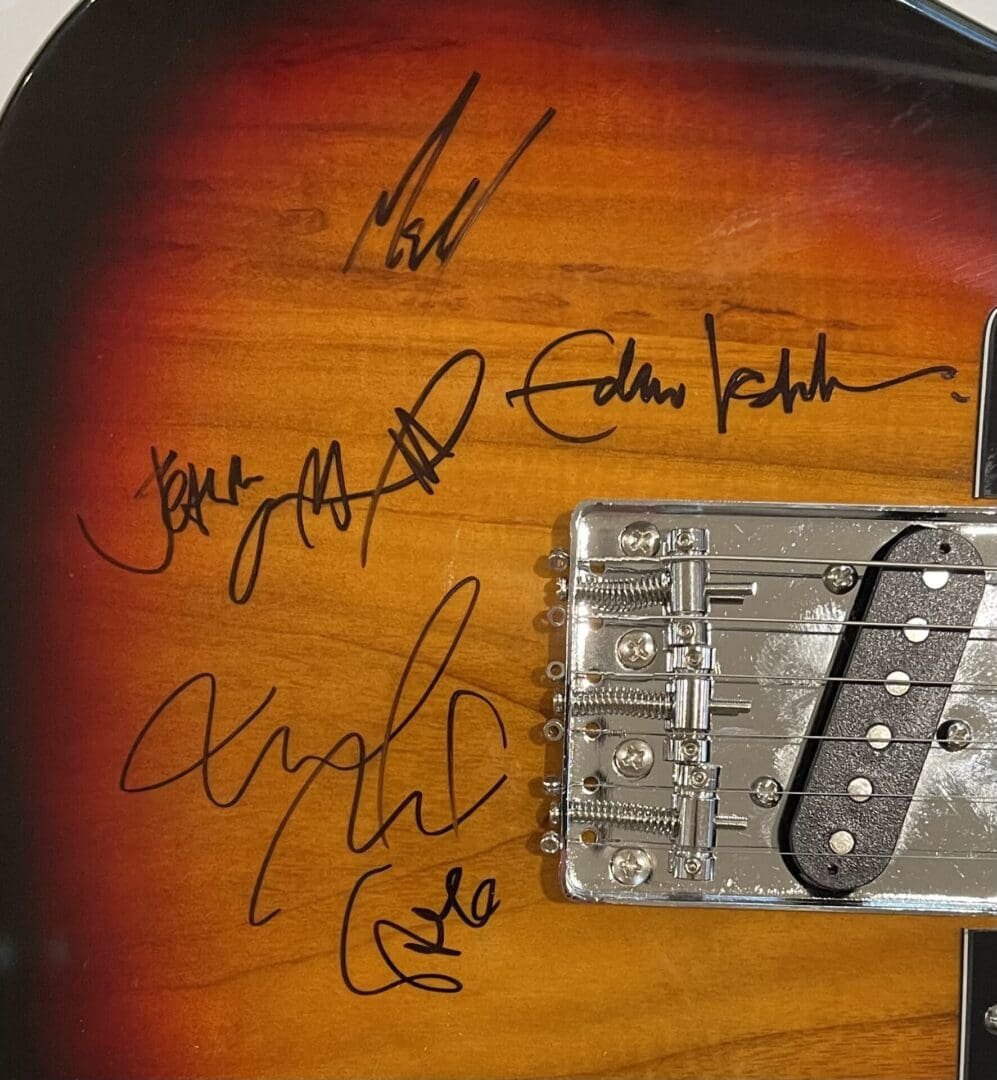 Signed electric guitar with multiple autographs.