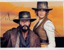 Cowboy and cowgirl posing against sunset backdrop.