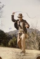 Adventurer with whip in outdoor setting.