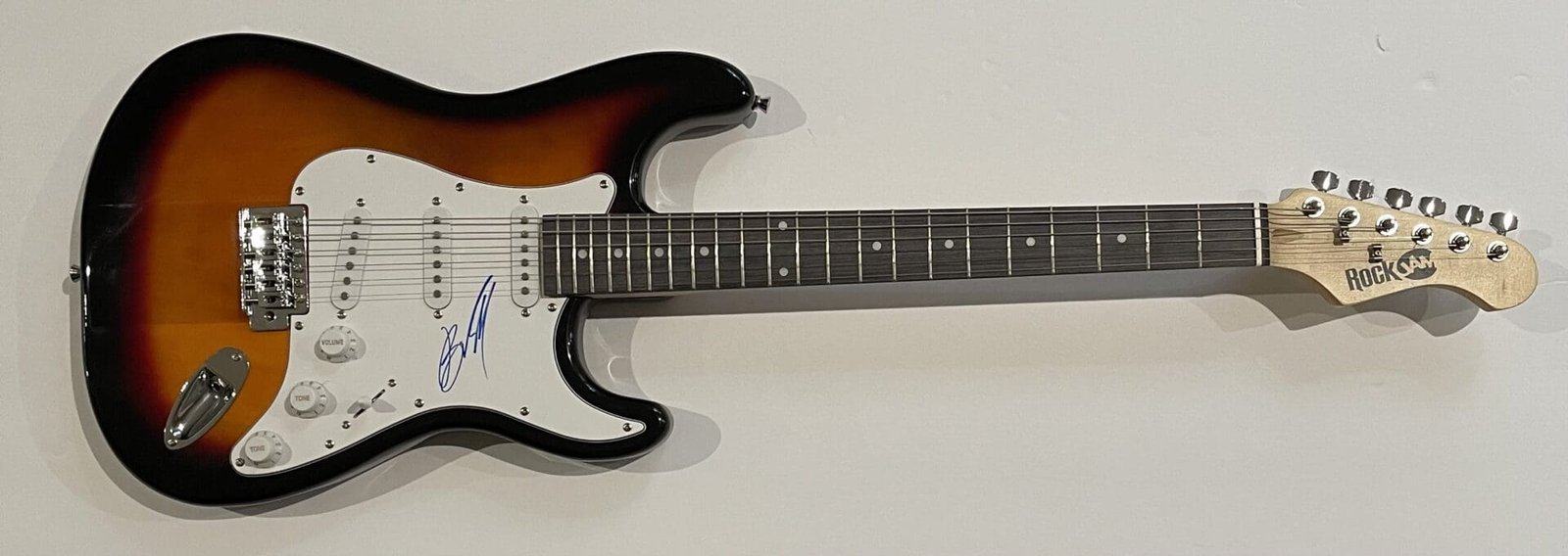 Sunburst electric guitar with signature on pickguard.