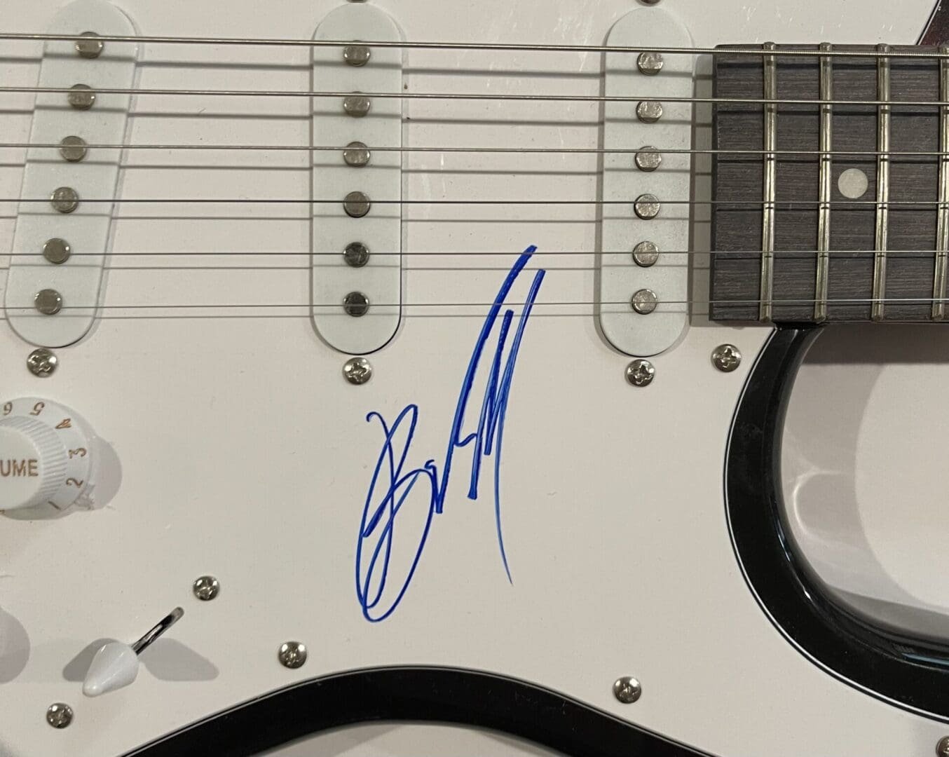 Electric guitar with blue autograph on body.