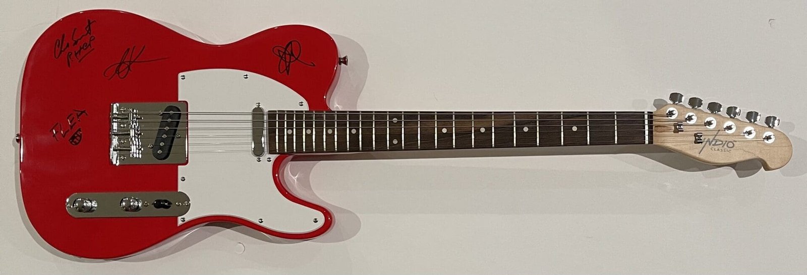 Red electric guitar with autographs on body.