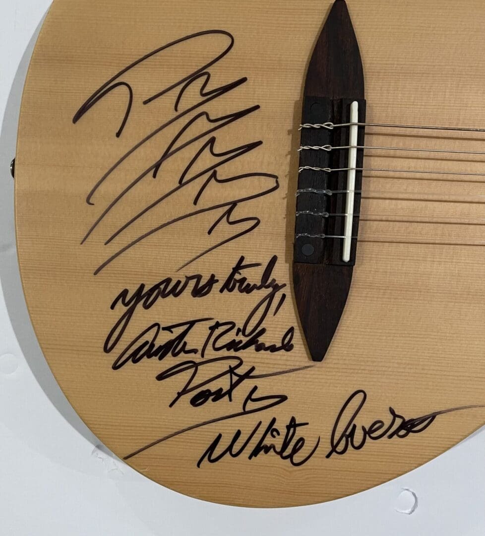 Autographed guitar with multiple signatures on top.