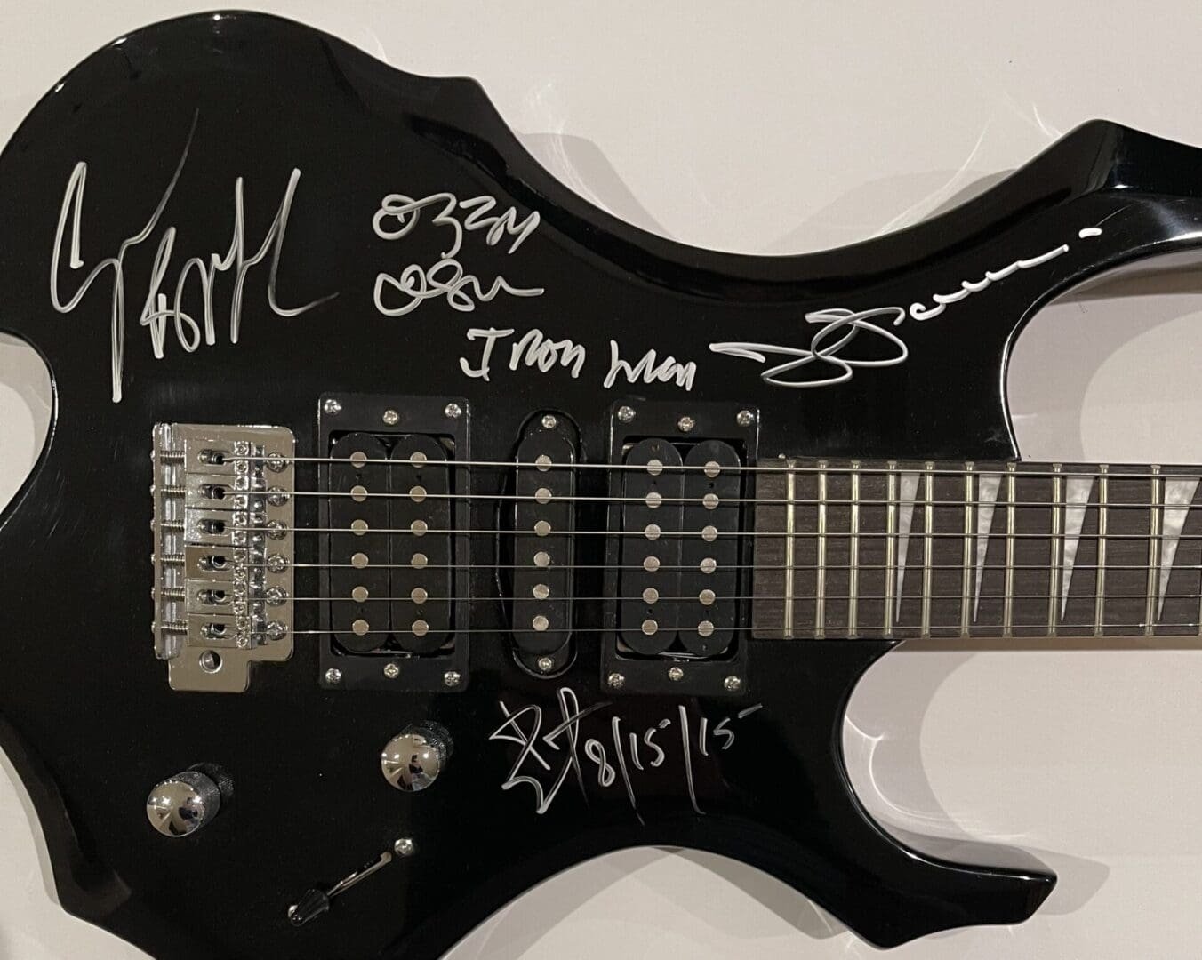 Black electric guitar with multiple signatures.