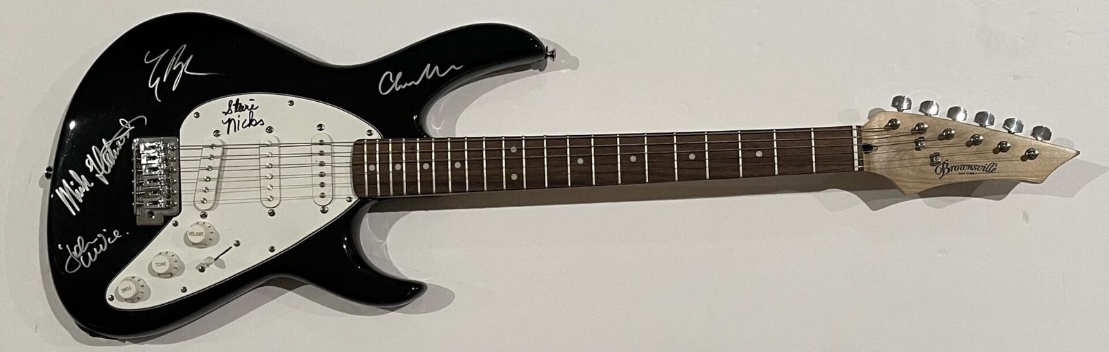 Black electric guitar with multiple signatures.