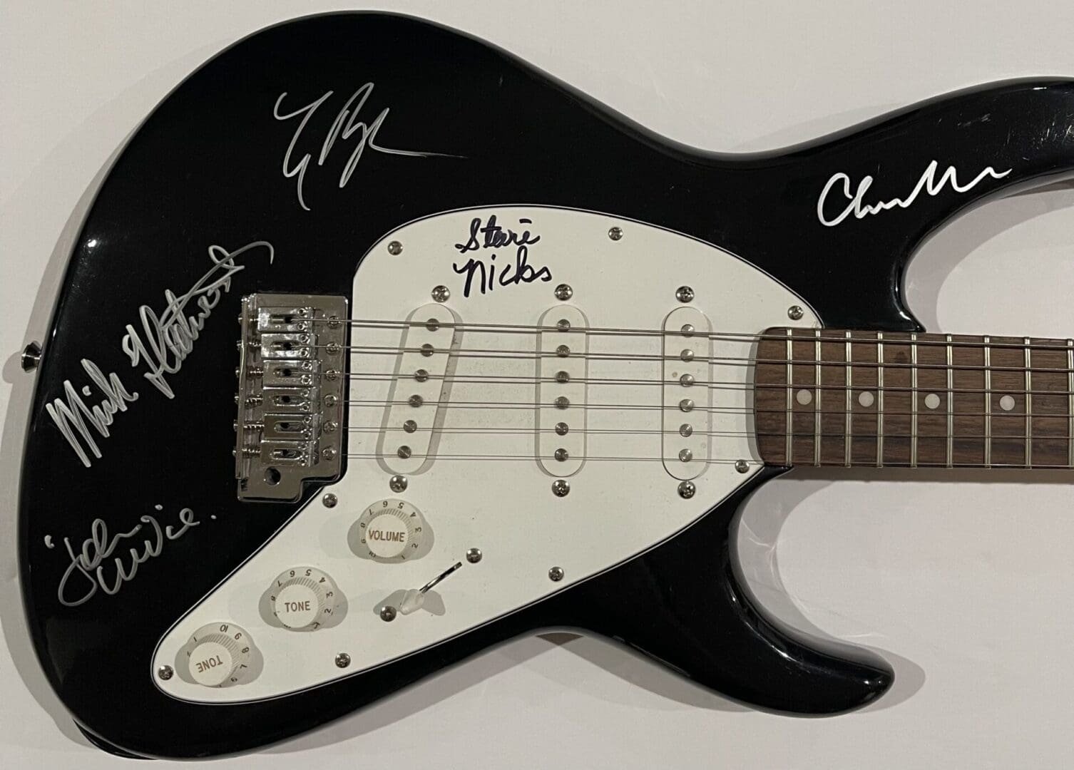 Black electric guitar with multiple signatures.