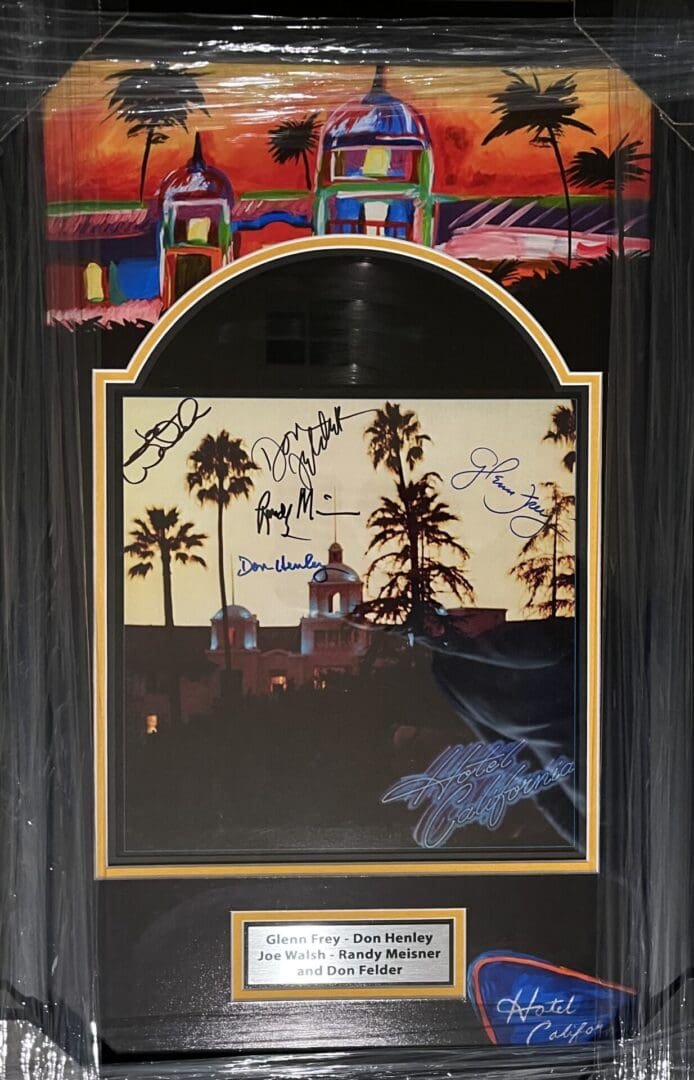 Framed album cover with signatures and sunset.