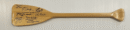 Wooden paddle with multiple signatures displayed horizontally.