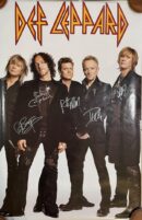 Band members with signed "Def Leppard" poster.
