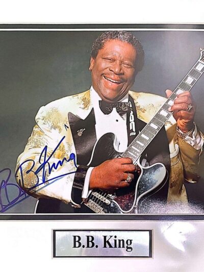 Smiling man with guitar and signed photograph.