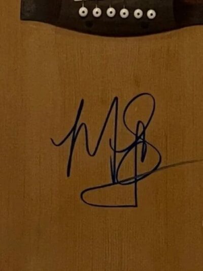 Autographed acoustic guitar with six strings.