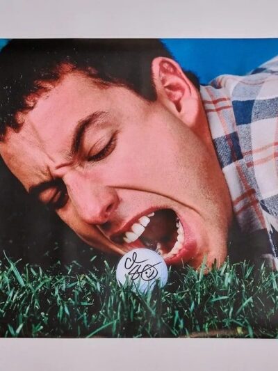 Man biting golf ball on grass.