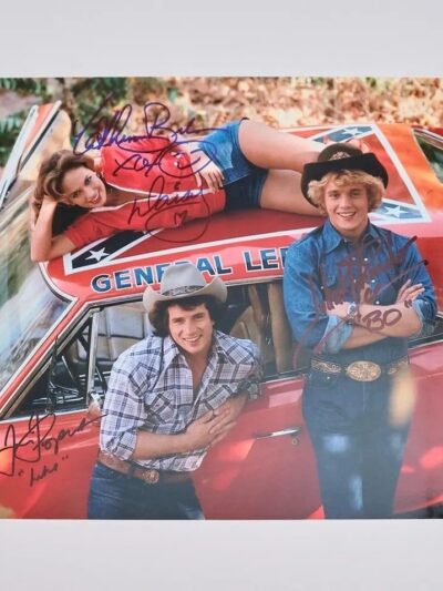Three people posing on a red car.