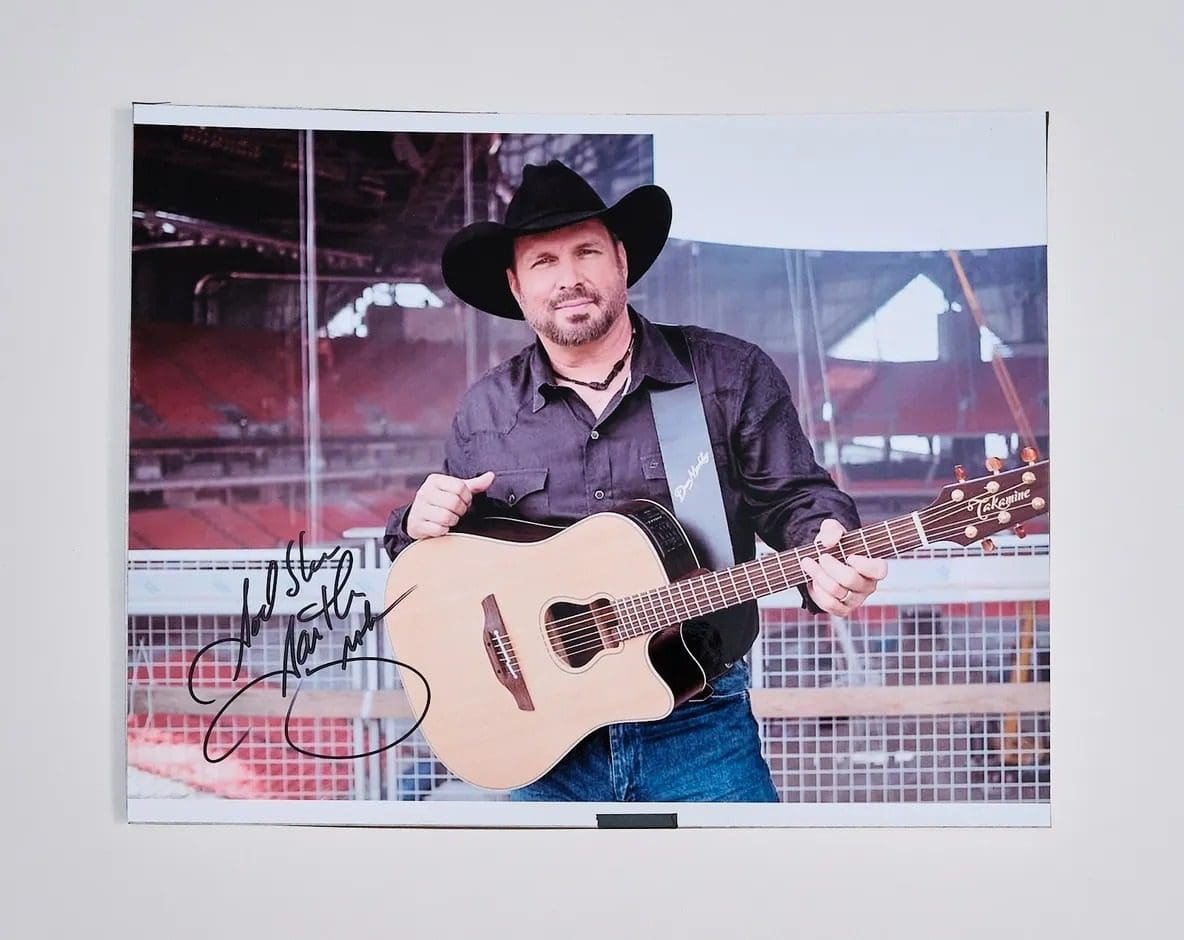 Man in cowboy hat holding acoustic guitar.