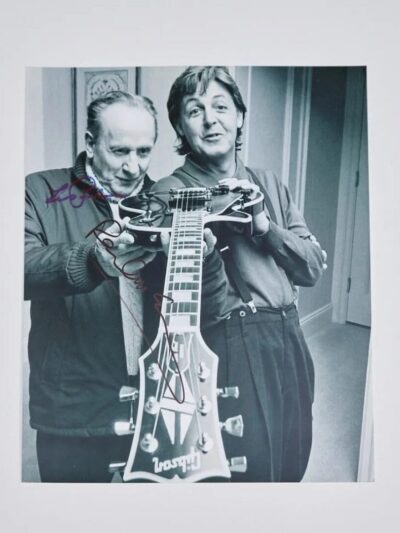 Two men holding a guitar together.