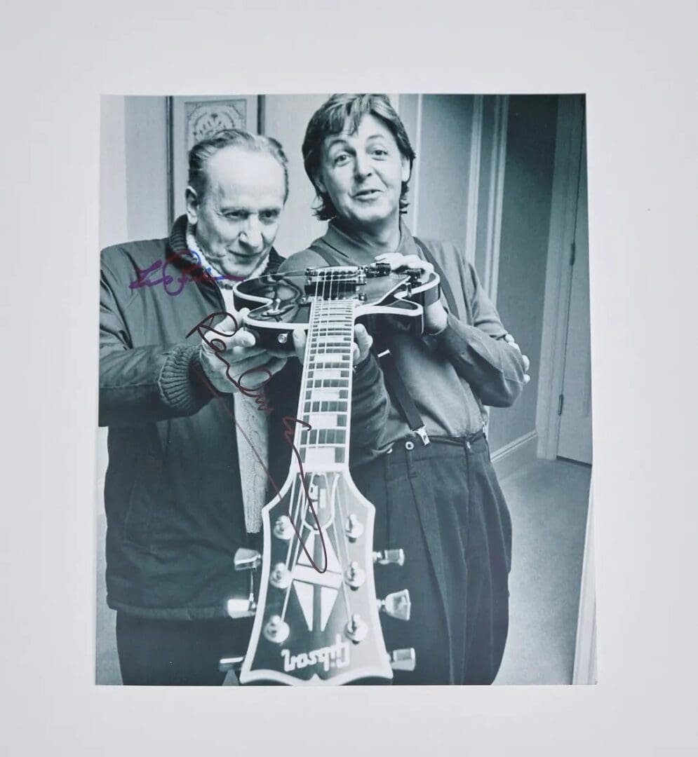 Two men holding a guitar together.