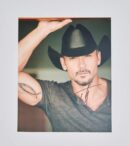 Man in cowboy hat with arm tattoo.