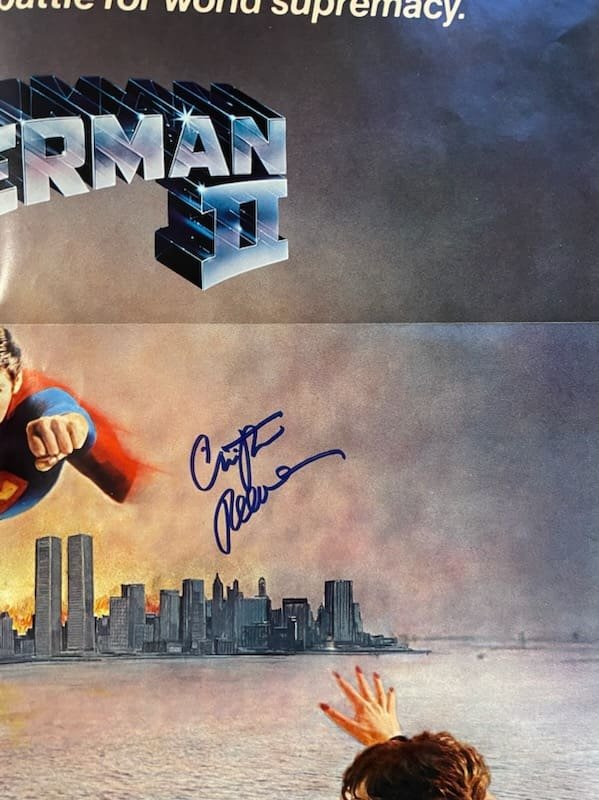 Signed Superman II poster with cityscape background.