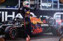 Race car driver celebrating beside Red Bull car.