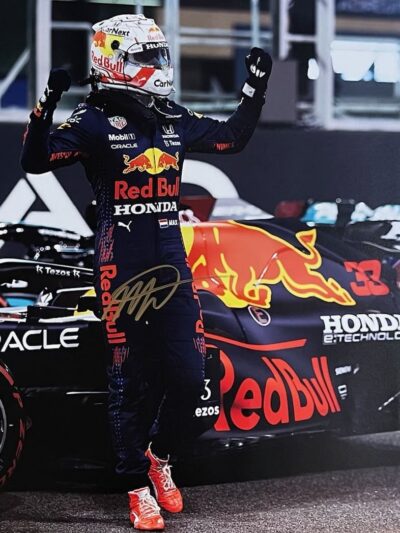 Race car driver celebrating beside Red Bull car.